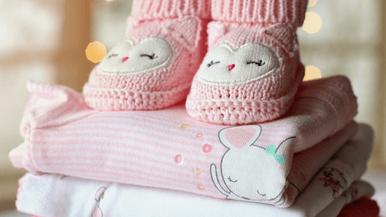 Pink baby booties and baby clothes.