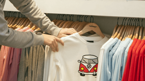 Woman looking at kid's clothing in a store - How To Save Money On Back To School Supplies List