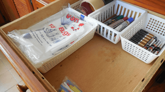 Place storage containers with the contents inside to organize the junk drawer.