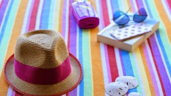 Hat, towel, sunglasses, sunblock and book