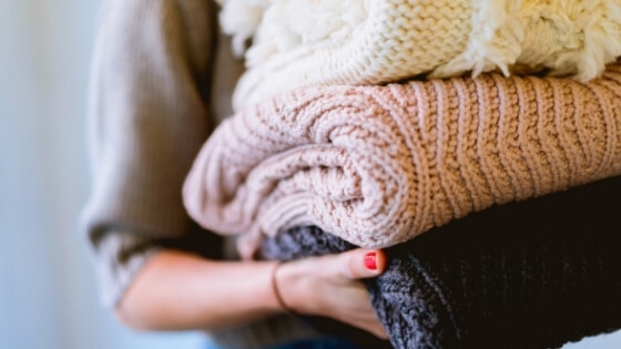 Stack of sweaters - Declutter your closet before moving.