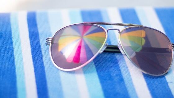 Aviator sunglasses on a blue striped beach towel.