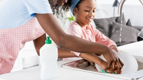 Mother and daughter hand washing dishes.