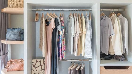 Clothes and bags in a small closet.