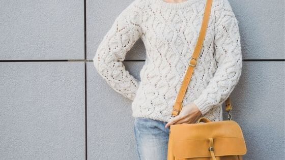 Woman wearing a white sweater and bag